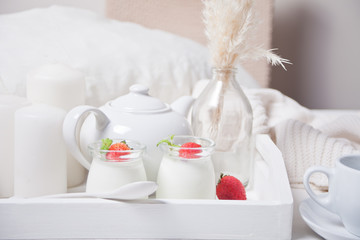 Two portions natural homemade yogurt in a glass jar with fresh strawberry on the white wooden tray