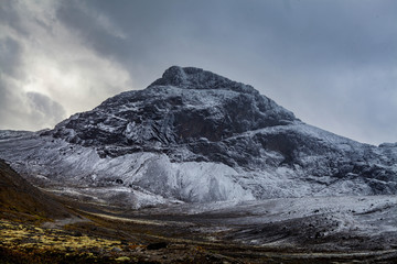 Mountain landscape. Rocky shore of a mountain lake on a rainy autumn day. First snow