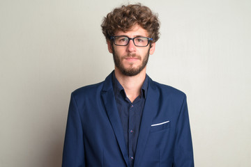 Face of young bearded businessman with eyeglasses in suit