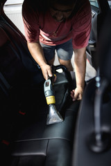 An auto service worker prepares and cleans the car seat