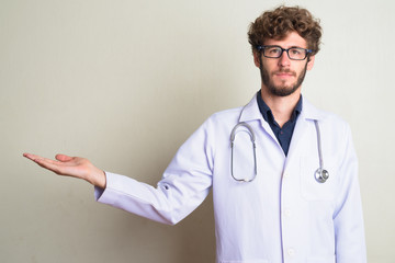Young bearded man doctor with eyeglasses showing something
