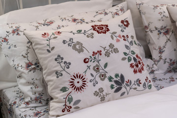 Modern white fabric pillows with beautiful embroidered flower patterns on the bed interior decoration