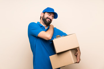 Delivery man with beard over isolated background suffering from pain in shoulder for having made an...