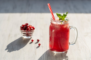 Fresh organic red smoothie in glass mug on white table, close up. Refreshing summer fruit drink. The concept of healthy eating. Cranberry and raspberry smoothie