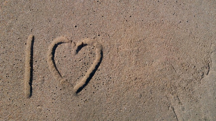 I love. Inscription on the sea sand I love for the background. Used for travel, vacation, additional text.