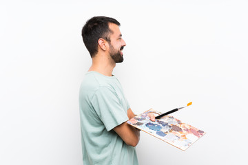 Young artist man holding a palette over isolated background in lateral position