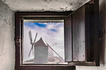 Windmill Seen Through A Open Window Of Another Mill With Fog In Consuegra. December 26, 2018. Consuegra Toledo Castilla La Mancha Spain Europe. Travel Tourism Street Photography.