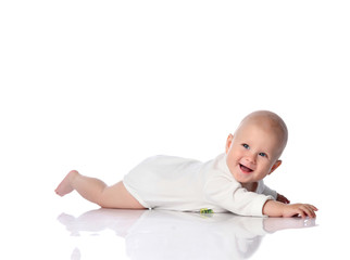Smiling infant child baby toddler in white bodysuit lying on his stomach crawling, trying to reach something on white