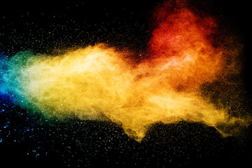 Yellow red blue powder explosion cloud on black background. Freeze motion of color dust  particles splashing.