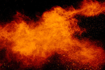 Yellow red powder explosion cloud on black background. Freeze motion of color dust  particles splashing.