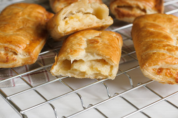 Savory cheese and onion puff pastry rolls fresh out of the oven cooling on a cooking trivet a vegetarian alternative to the usual sausage roll