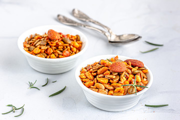 Roasted Mixed Nuts in a White Bowl Garnished with Fresh Rosemary on White Background. Healthy Eating, Healthy Food Photography..