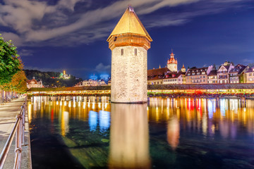Lucerne, Switzerland. Night view of Water Tower Wasserturm and Chapel Bridge Kapellbrucke over the river Reuss during night city lighting in Old Swiss Town of Luzern.