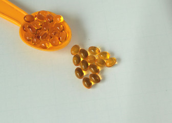  Multivitamin oil in soft capsules in a spoon on a white background