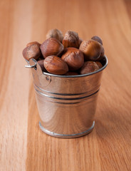 Hazelnuts in a small bucket on a wooden table