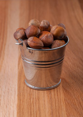 Hazelnuts in a small bucket on a wooden table
