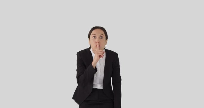 Shocked businesswoman with finger on lips over white background