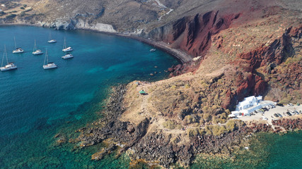 Fototapeta na wymiar Aerial drone photo of iconic famous red rocky volcanic beach with deep turquoise sea visited by sail boats, Santorini island, Cyclades, Greece