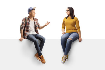 Male student sitting on a panel and talking to a female friend