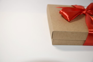 On a white background a gray gift cardboard box and a red ribbon.