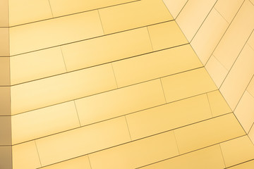 Bottom view of warm yellow color tiled wall of pyramid structure