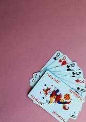 Cards for playing poker lie at the bottom of a pink background. Place for text.