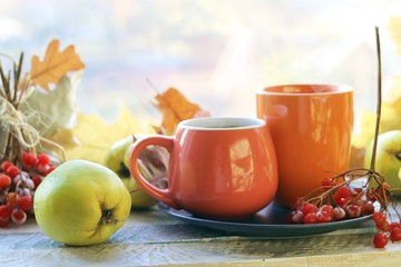 Two cups of tea, fruits, berries, leaves on a wooden table on a window background, romantic autumn composition, home comfort concept, healthy food