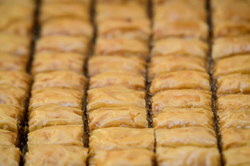 Close up of traditional oriental sweet pastry cookies known as backlava, Turkish desert with sugar, honey, walnuts and pistachio, in display at an weekend street food market, top view, soft focus
