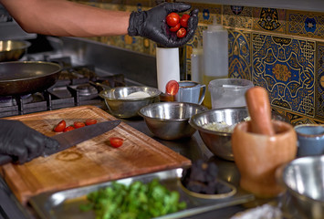 Food concept. The chef cuts the tomatoes, prepares the ingredients for the dish on the table in the kitchen.