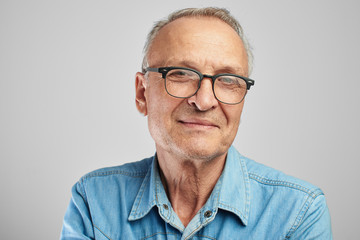 Portrait of a Caucasian elderly man with glasses smiling on a white studio background. Handsome...
