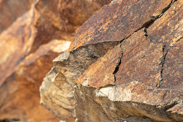 Rock texture background. Close-up of colorful red brown rock layers with selective focus on the foreground and a blurry background. Beautiful stone texture. Lloret de Mar, Catalonia, Spain.