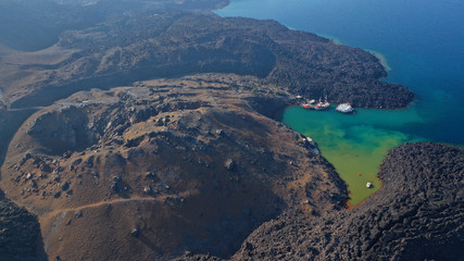 Aerial drone photo of black volcanic crater turning sea to green