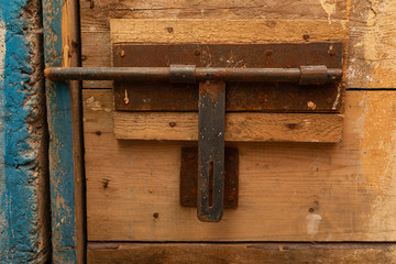 An old rusty latch of a rough wooden door