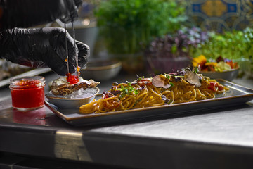 The chef garnishes with red caviar a seafood spaghetti dish. Selective focus.