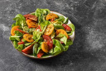 Healthy vegetable salad from fresh vegetables of tomatoes, cucumbers, onions, spinach, lettuce on a plate. Diet menu. View from above.