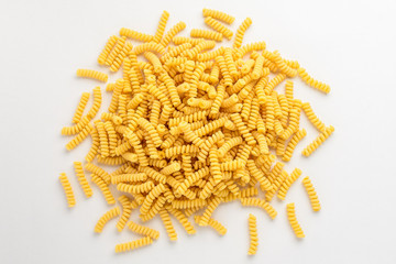 Obraz premium Group of dried fusilli Italian pasta in a round shape ready to be cooked, isolated on white table, with view from above 