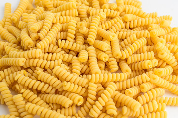 Close up of dried fusilli Italian pasta in a round shape ready to be cooked, isolated on white table, with view from above 