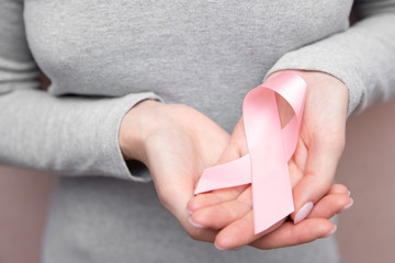 Girl hands holding pink breast cancer awareness ribbon on gray background. Concept healthcare and medicine beauty