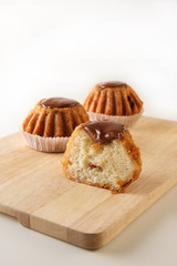 Three freshly baked sweet rum cakes with a cut on the wooden board with copy space, selective focus, vertical image