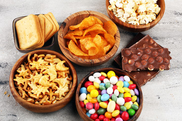 Salty snacks. Pretzels, chips, crackers in wooden bowls and candy and chocolate on table