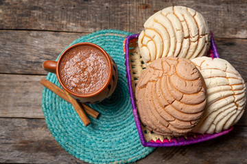 Mexican hot chocolate with sweet conchas bread on wooden background