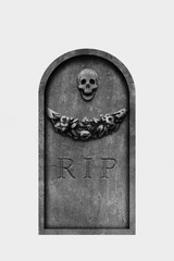 Decorated, oval granite tombstone on white background with engraved R.I.P. text, skull and carved stone flowers