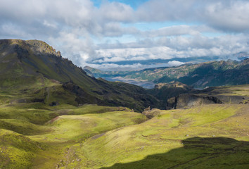 Landscape of Godland and thorsmork with rugged green moss covered rocks and hills, bending river canyon, Iceland, Fimmvorduhals hiking trail. Summer blue sky white clouds