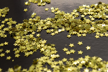 Fototapeta na wymiar This is a photograph of Gold star sequins placed on a Black background