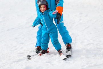 Fototapeta na wymiar little girl learns to ski with the help of an adult