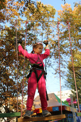 little girl overcomes rope obstacles in the trees