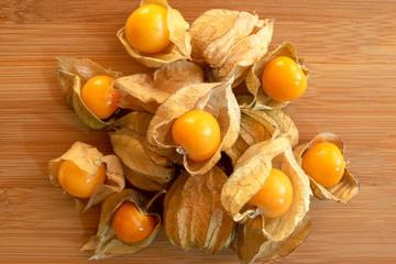 Pile of golden berries isolated on light wooden table. Physalis fruit. Golden berries. 