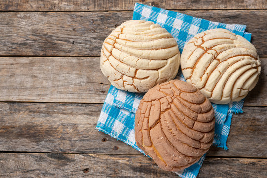 Mexican sweet bread: vanilla and chocolate conchas on wooden background