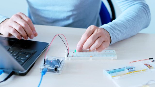 Innovation technology. Program development. QA engineer testing hardware with microcontroller.