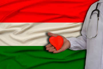 photo of a doctor with a stethoscope with a heart in his hand against the background of the...